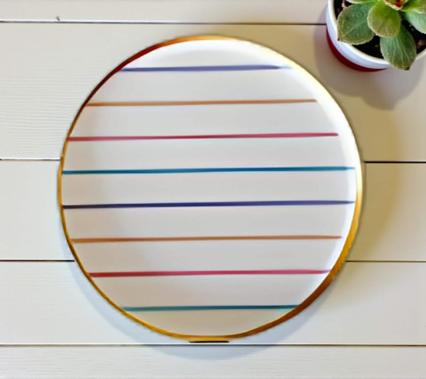 Round high quality paper plate with colorful stripes on a wooden surface