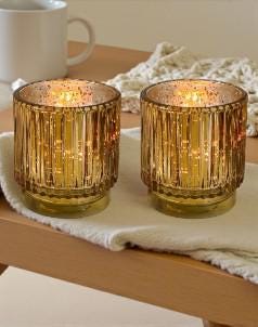 Two gold candle holders with lit candles on a wooden surface.