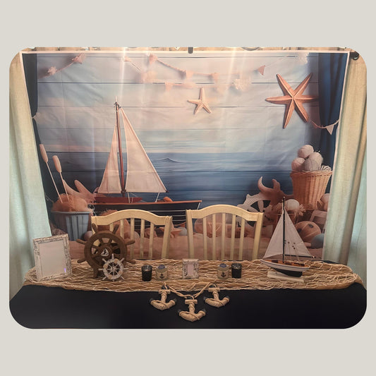 Decorative scene with sailboats, anchors and a ship wheels on a navy blue surface with a scenic background.