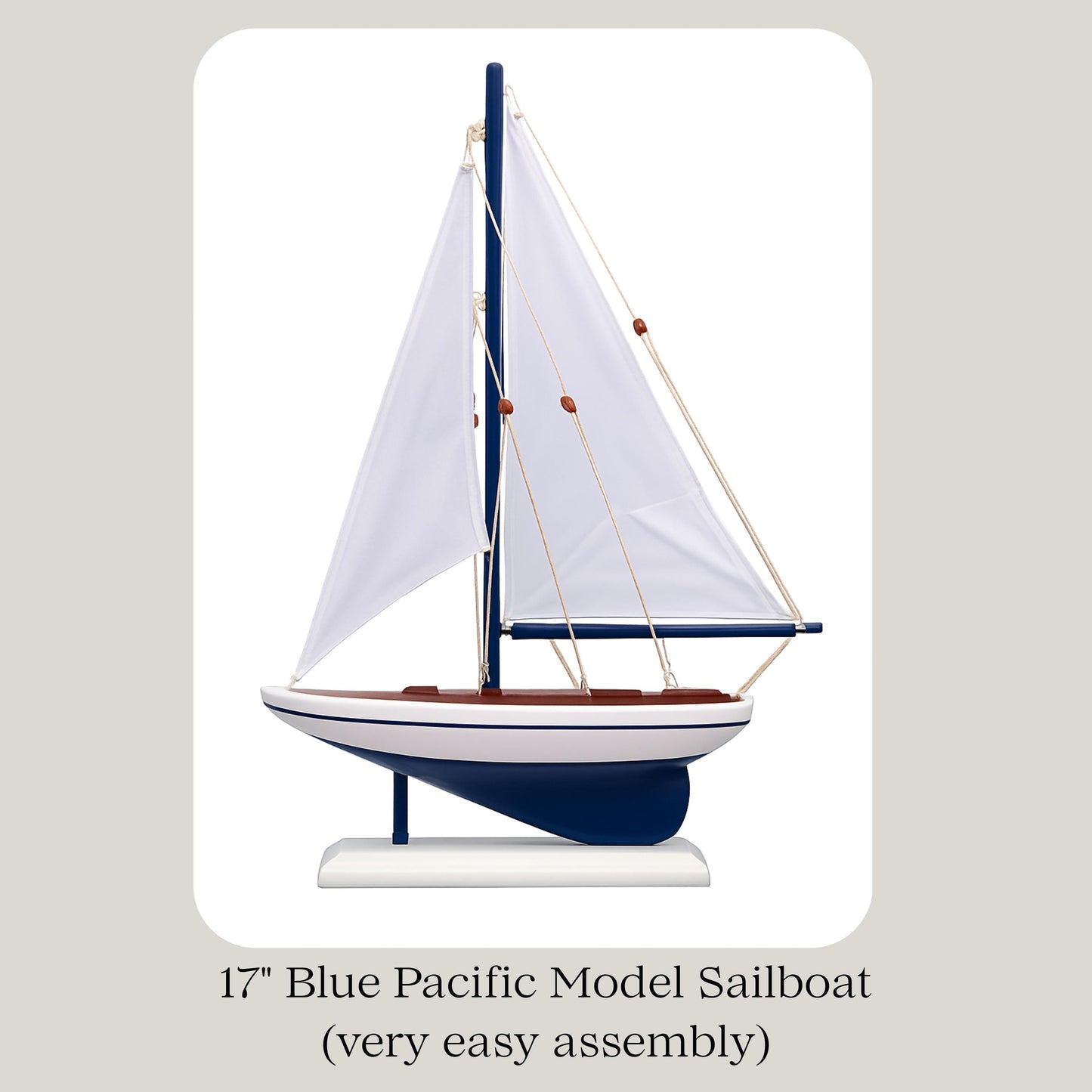 Model sailboat with blue hull and white sails on a beige background