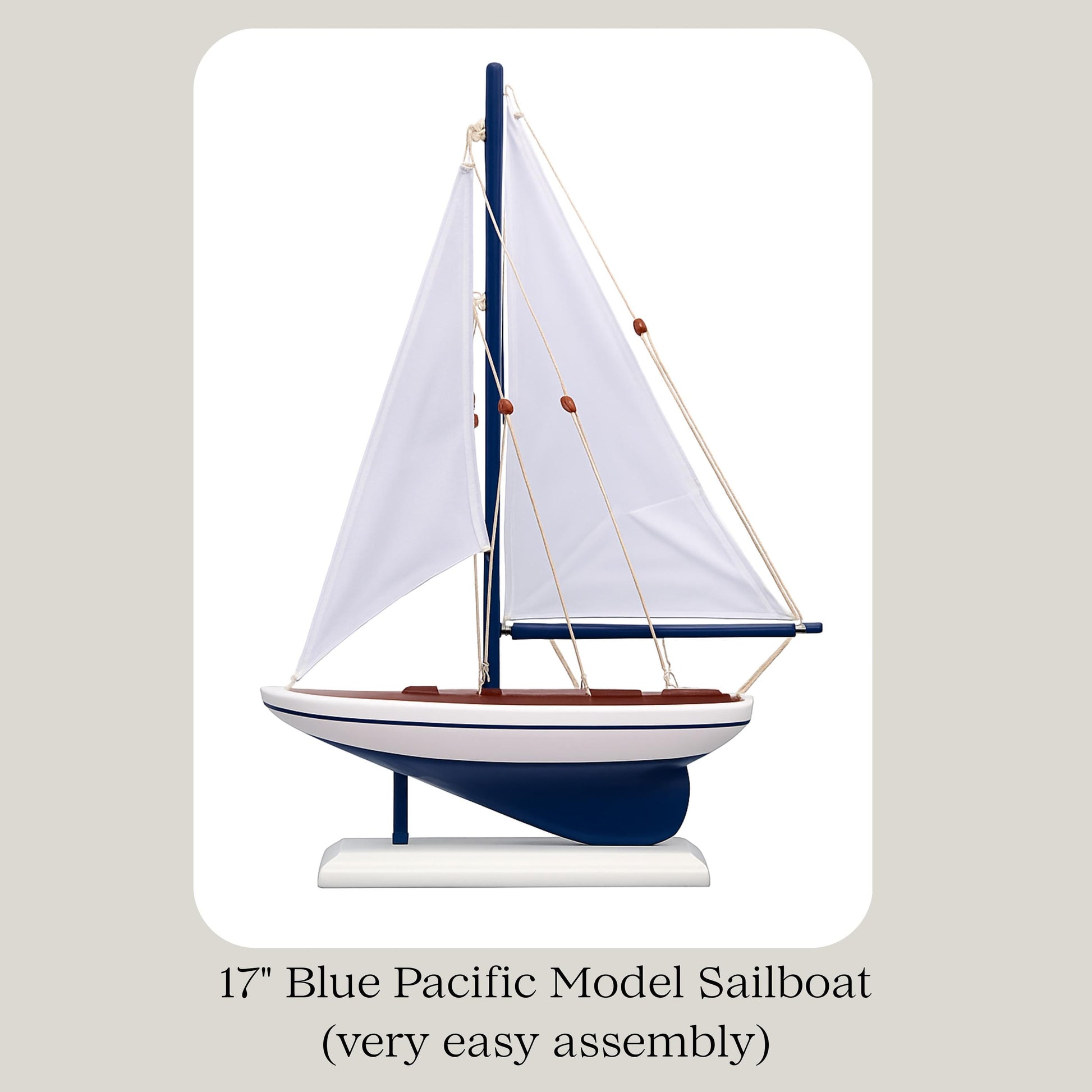 Model sailboat with blue hull and white sails on a beige background