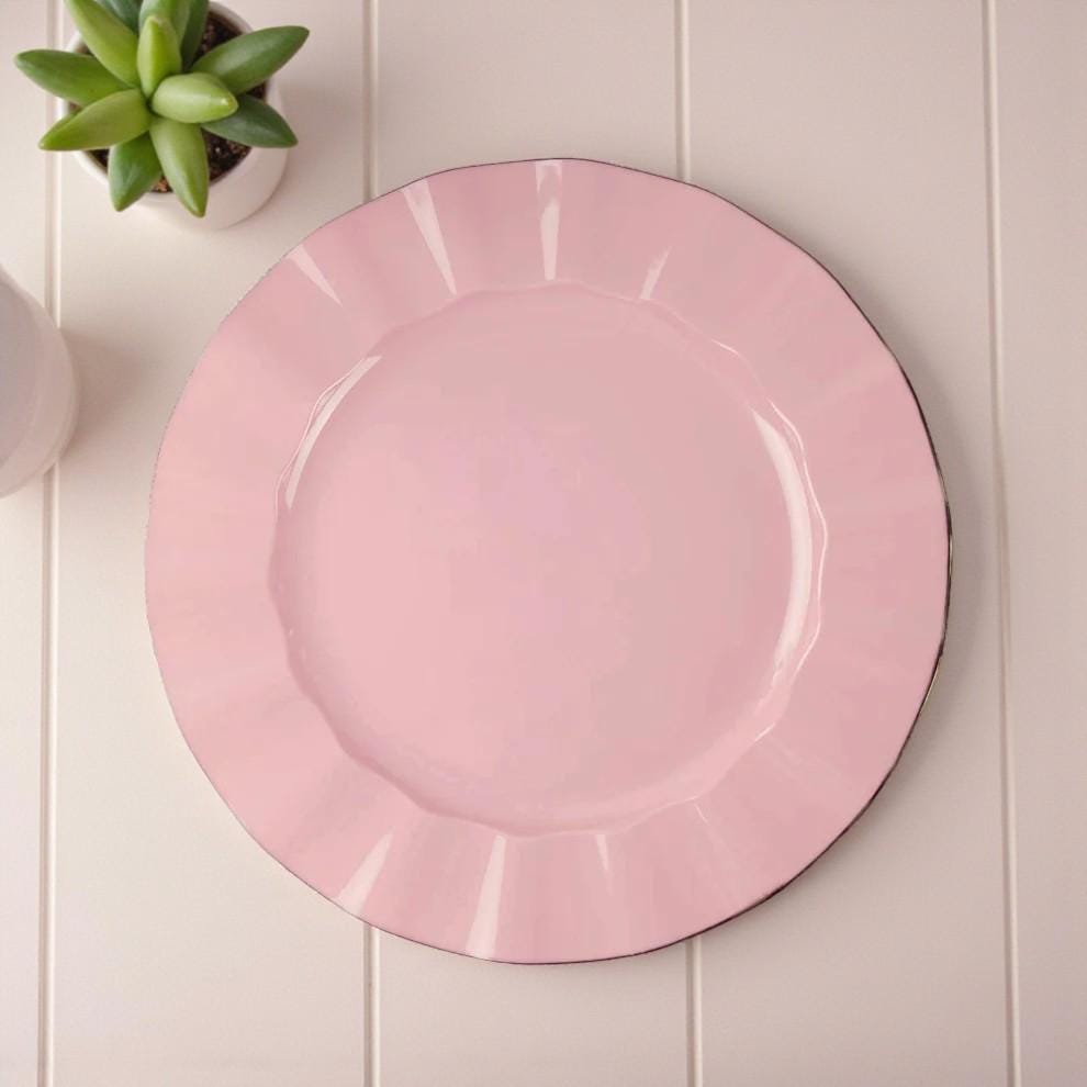 Pink high quality lunch/dinner plate on a light wooden surface with a small plant in the corner.