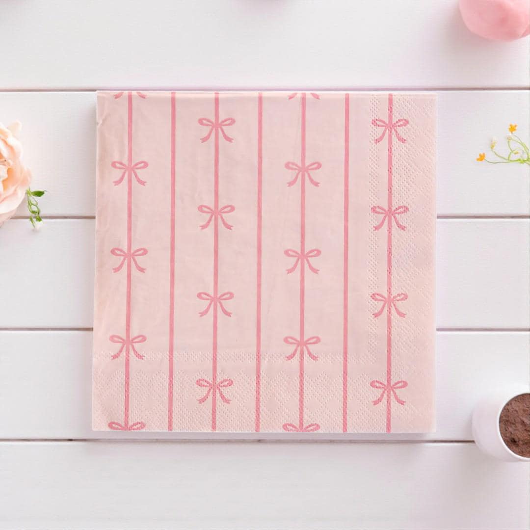 Pink napkin with bow pattern on a white wooden surface