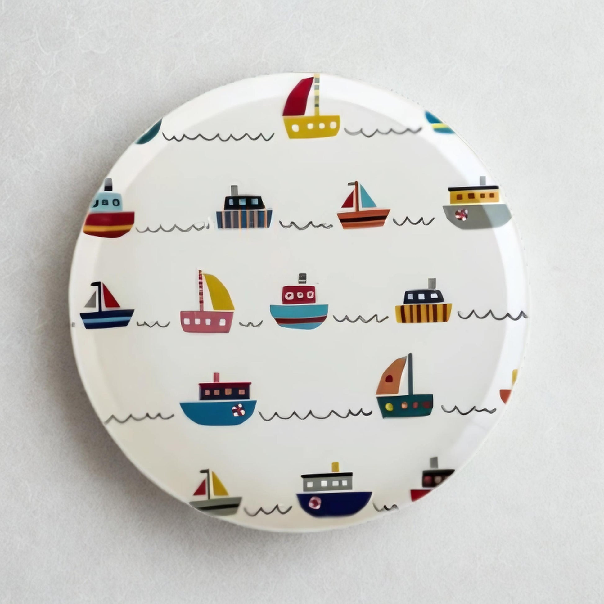 Round plate with colorful boat pattern on a white background